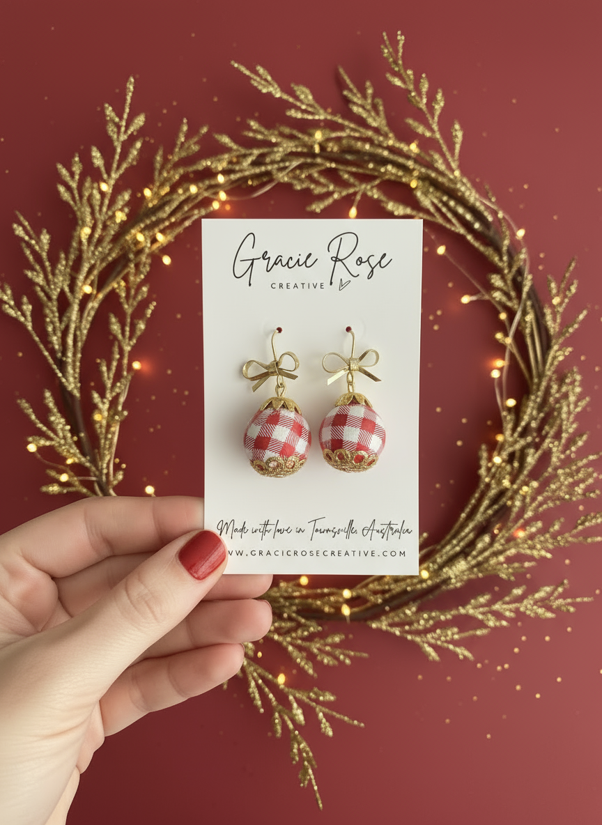 Gingham Baubles red earrings by Gracie Rose Creative displayed on a card surrounded by festive greenery, emphasizing their handmade quality.