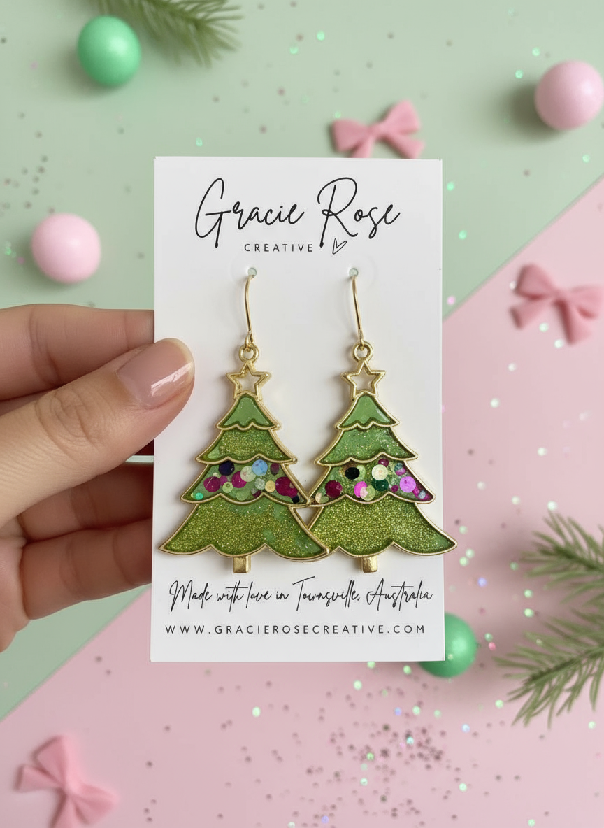 Hand holding a pair of Oh Christmas Tree… green earrings by Gracie Rose Creative, beautifully displayed on a branded card with a festive theme.
