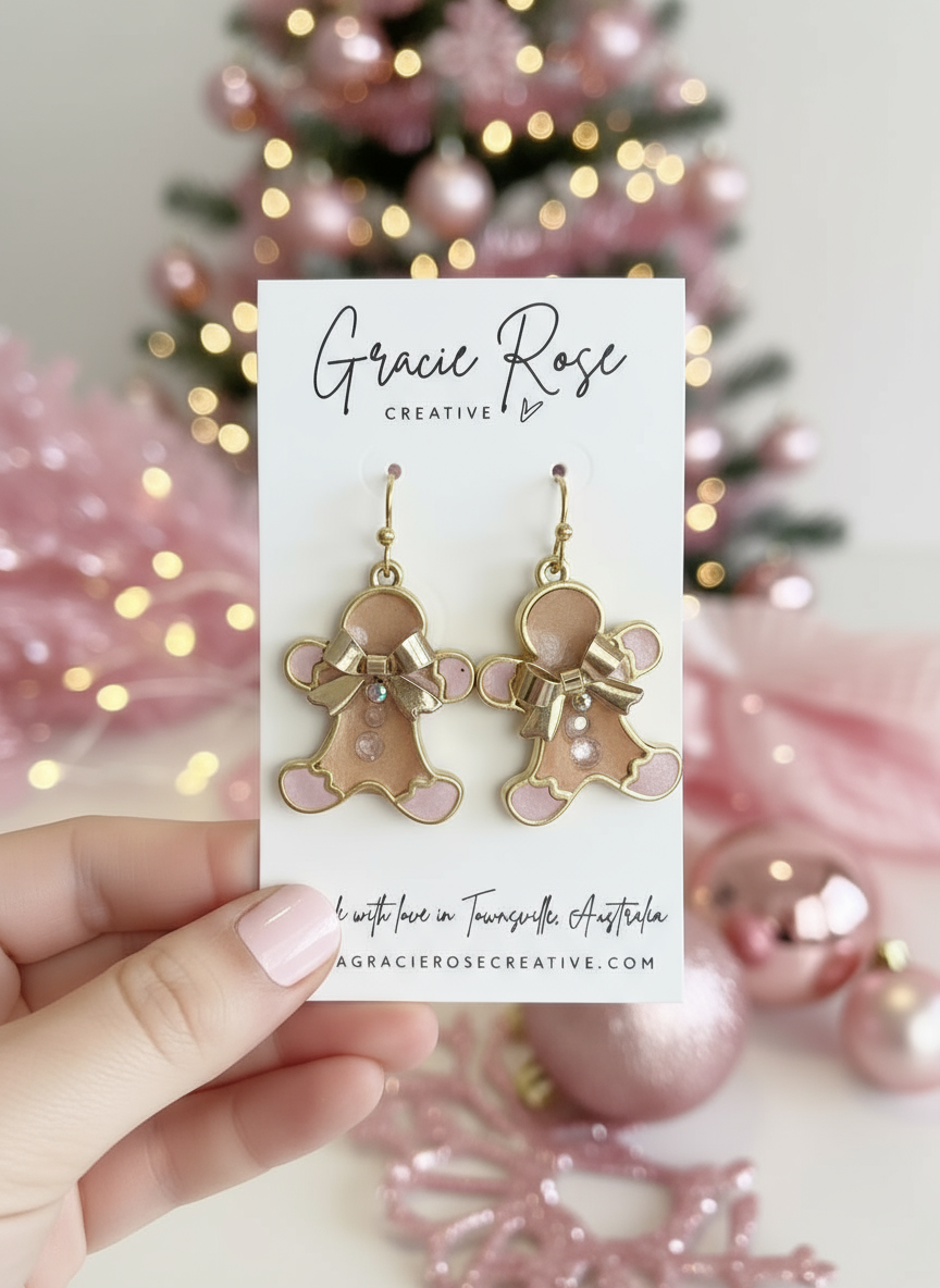 Close-up image of pink gingerbread men earrings by Gracie Rose Creative, displayed on a festive background with Christmas decorations, showcasing their handmade beauty.
