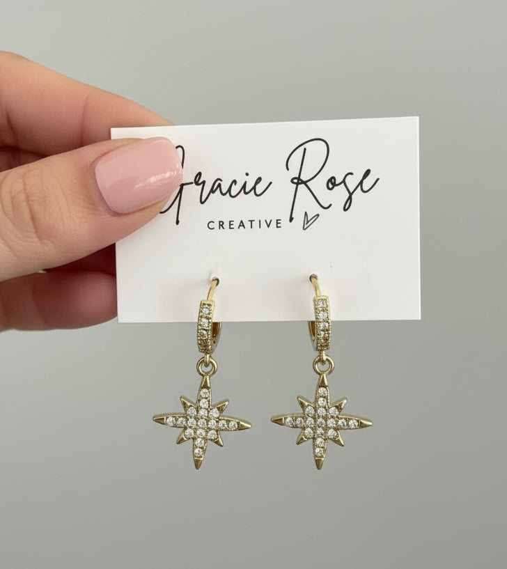 Close-up of North Star Huggies earrings by Gracie Rose Creative, featuring gold plating and shimmering diamantés in a star design.