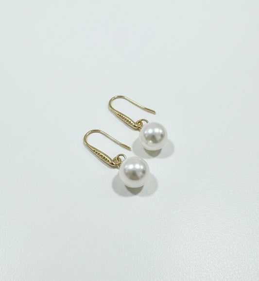 The Heiress Pearl drop earrings by Gracie Rose Creative featuring lustrous man-made pearls on gold-tone hooks against a neutral background.