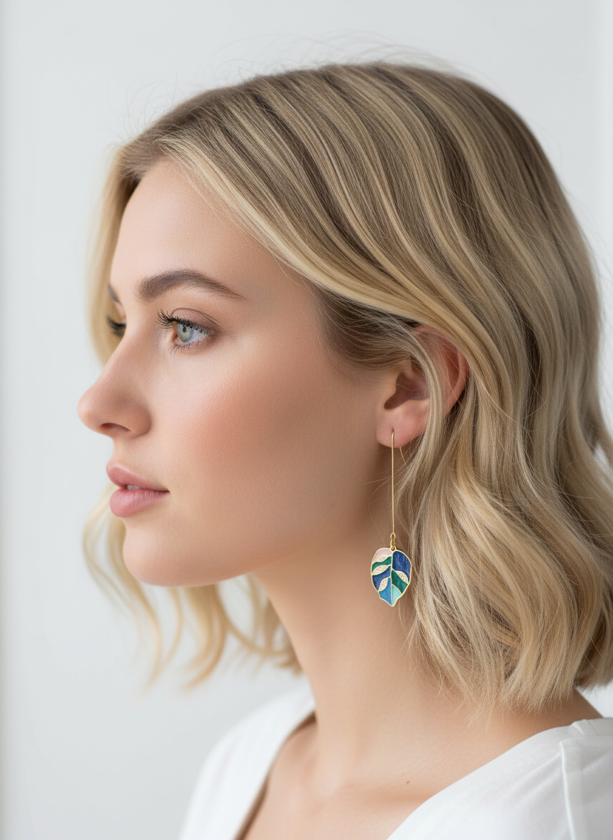 A model showcasing Blue Bloom Leaves earrings by Gracie Rose Creative, displaying layered shades of blue and gold accents. The earrings have a nature-inspired design, perfect for everyday wear.