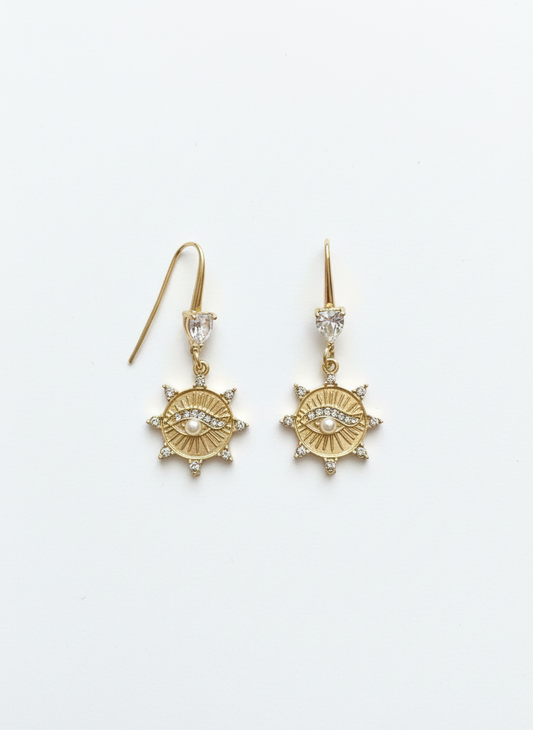 Eternal Love Evil Eye Drop Earrings featuring a gold sunburst medallion with a sparkling evil eye center and pearl accent.