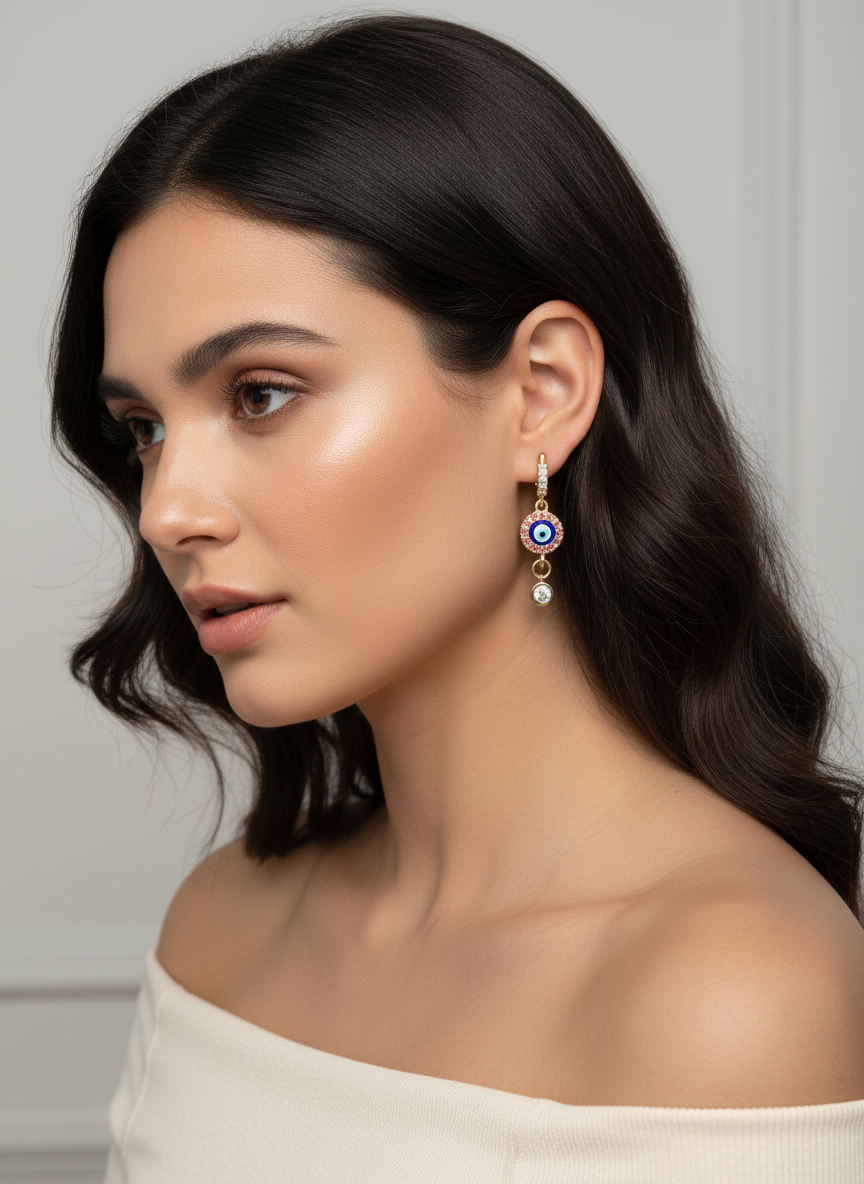 Evil Eye Luxe Drop Huggie earrings featuring a gold finish, pink stones, and a crystal drop for added sparkle.