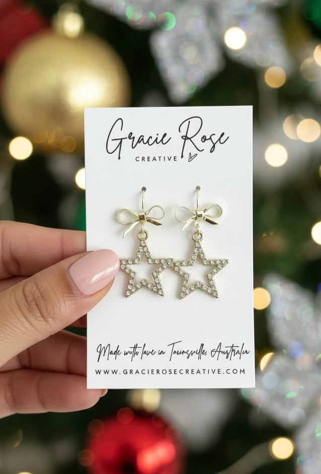 Close-up of Starlight Baubles earrings by Gracie Rose Creative, presented on a brand card, surrounded by festive decorations.