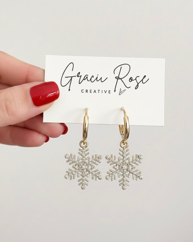Sparkle Snowflake Huggies by Gracie Rose Creative, displayed elegantly with a branded card, featuring adorable gold snowflake earrings.