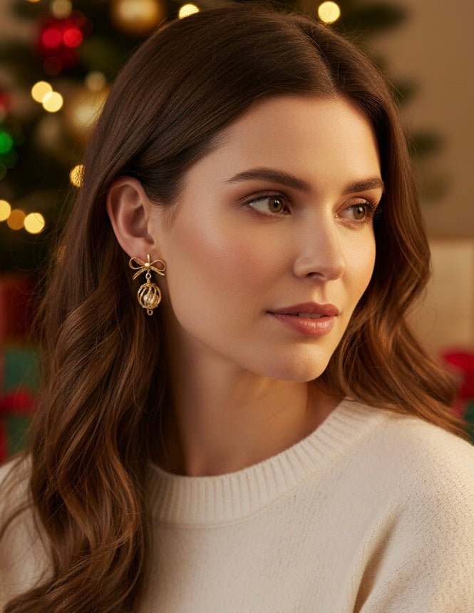 Model showcasing The Golden Baubles earrings by Gracie Rose Creative, complemented by a festive holiday background.