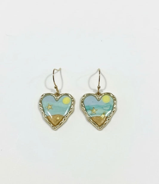Handcrafted heart earrings titled 'Seaside Sweetheart' by Gracie Rose Creative featuring ocean blue and sandy tones with starfish details.