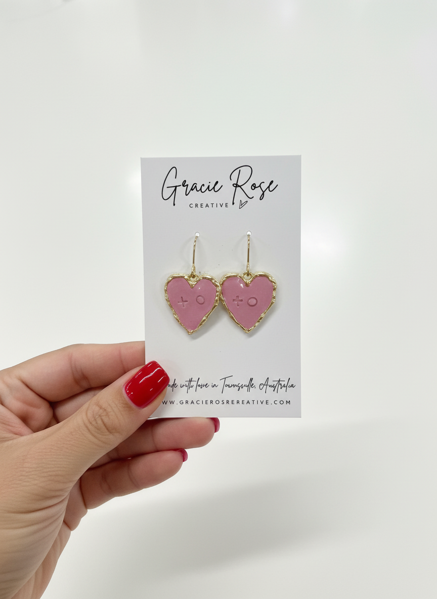 Mini XOXO earrings in pink, beautifully framed in gold tones, perfect for adding a sweet touch to any outfit.