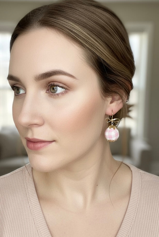 Model wearing Gingham Baubles pink earrings with gold bows, showcasing a stylish look, by Gracie Rose Creative.