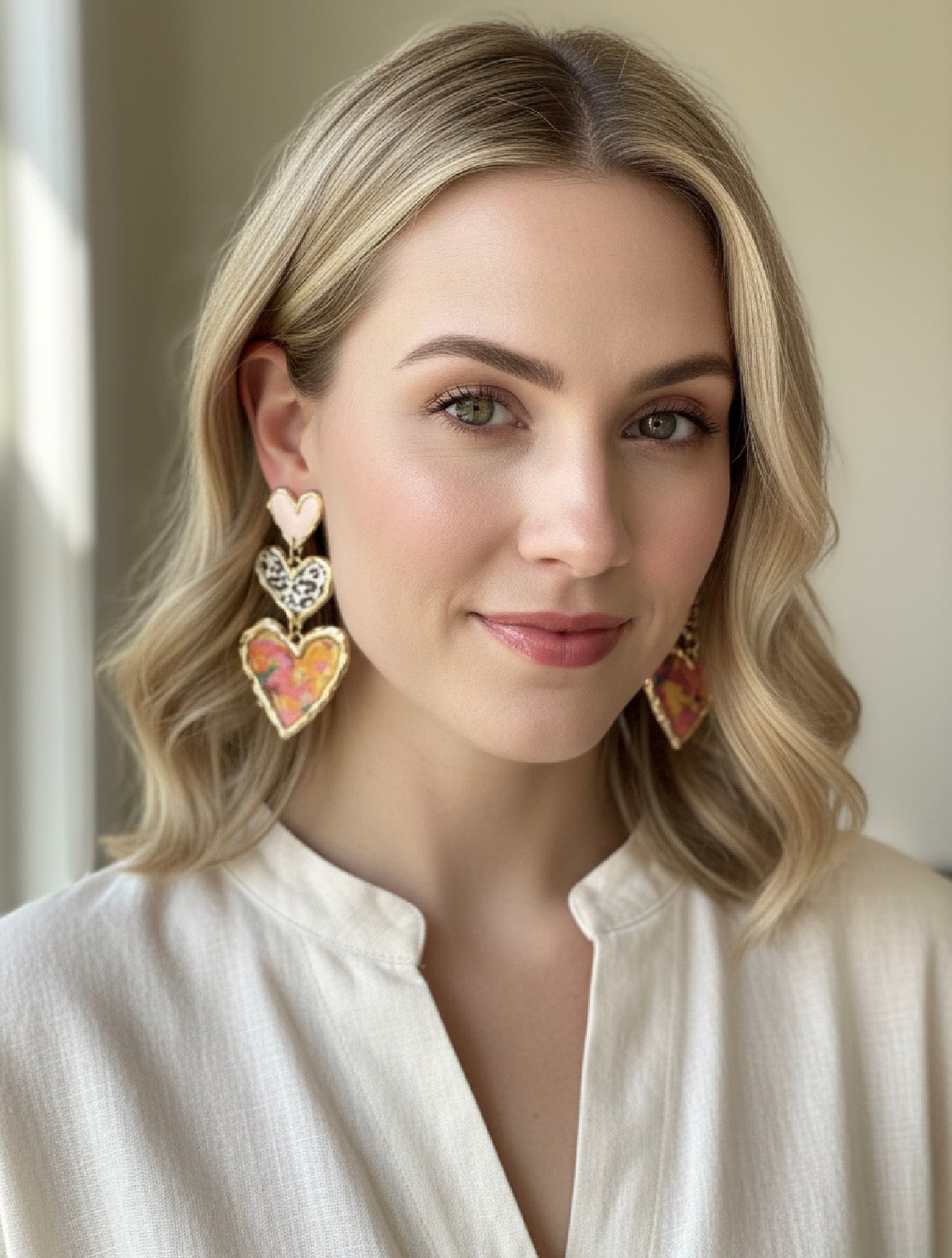 A model wearing Cross Your Heart pink floral earrings by Gracie Rose Creative, showcasing their stylish design and elegance.