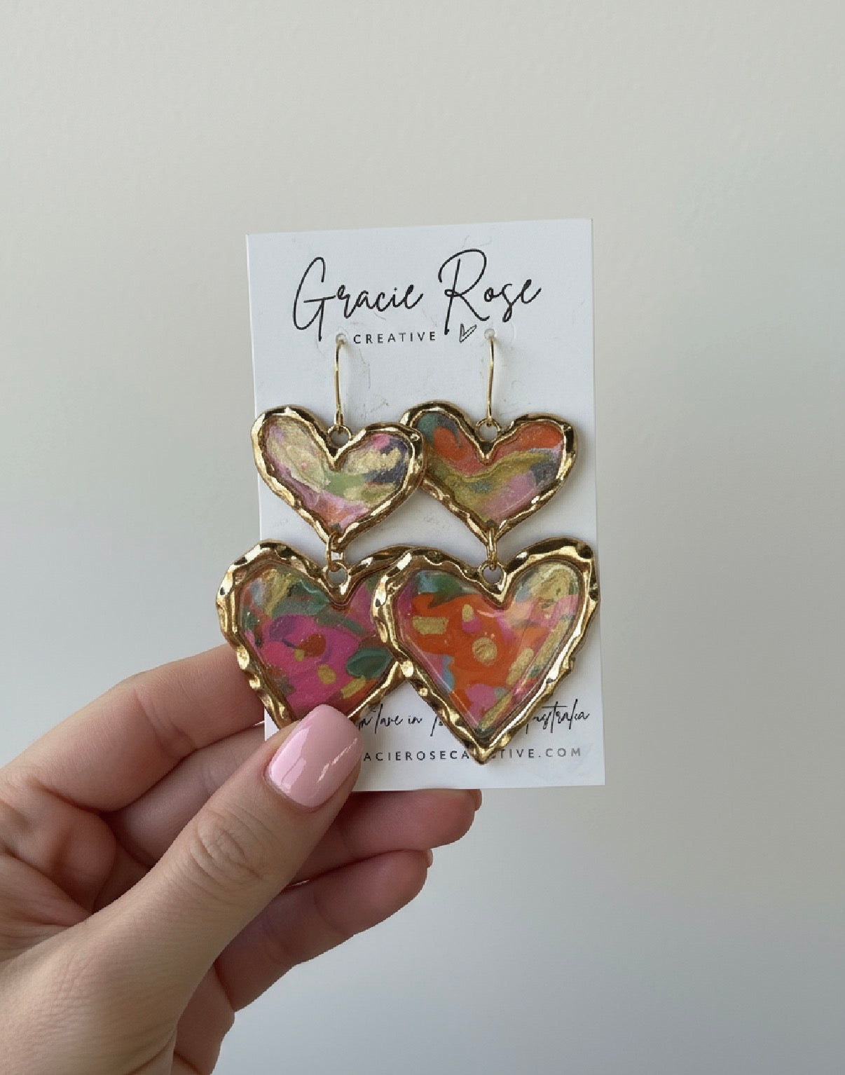 Colorful handmade polymer clay earrings by Gracie Rose Creative featuring a bold cross your heart design with gold accents.