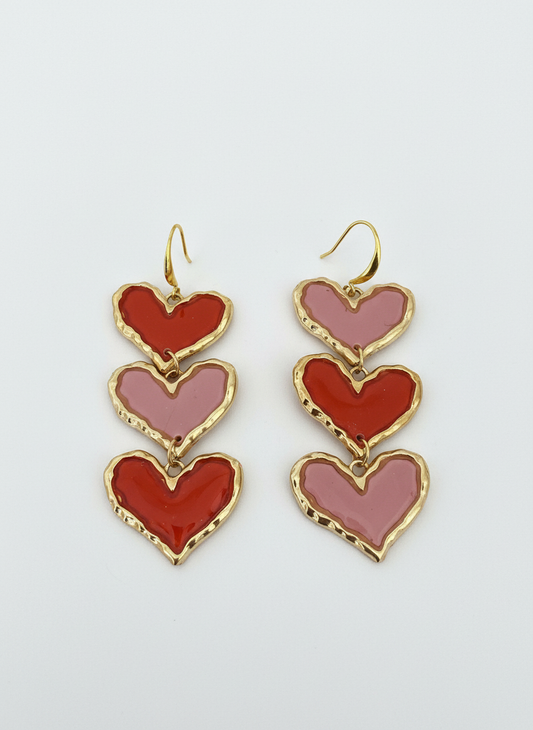 The Mega Sweetheart Stack earrings by Gracie Rose Creative featuring layered red and blush pink hearts framed in gold detailing, perfect for making a bold fashion statement.
